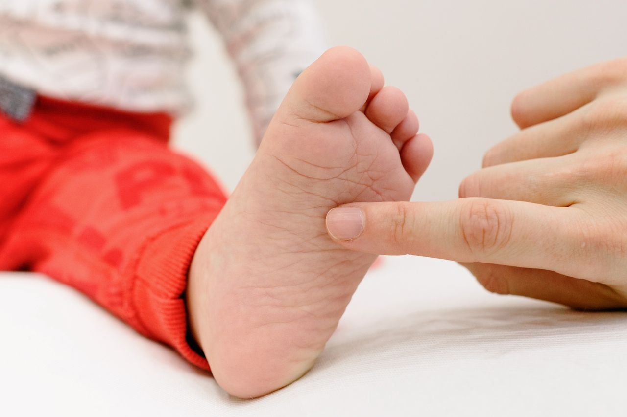 A touching moment between a baby's foot and an adult's finger, symbolizing care and connection.